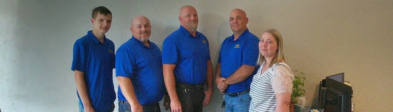 The InfoWest Richfield team of five in blue InfoWest shirts stands together against an office wall; Tiffany is at the right.