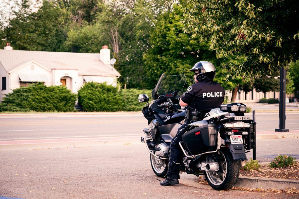 A police officer on a motorcycle parked along a tree-lined residential street