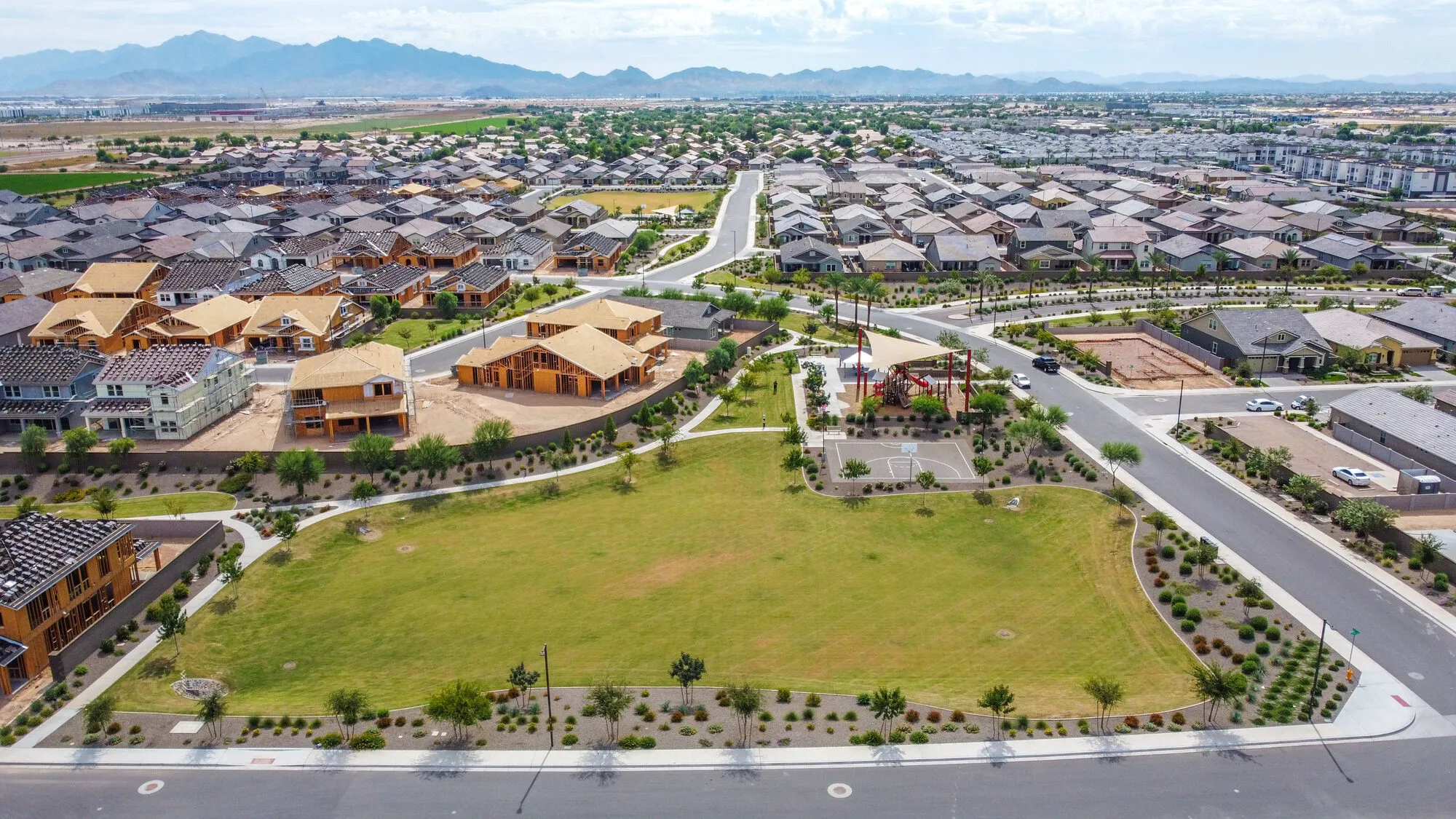 A new neighborhood of homes around a green park, with more homes under construction