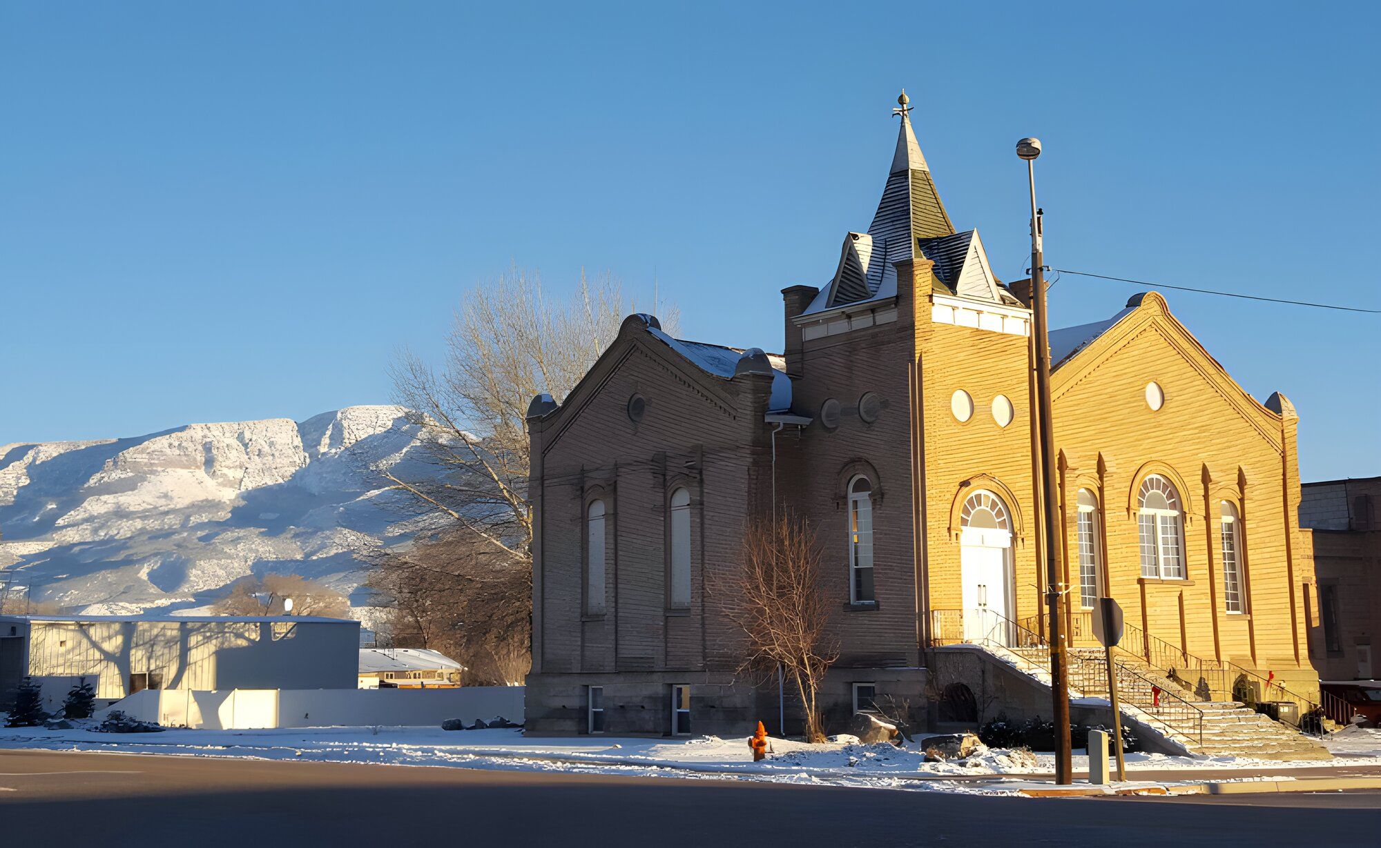 A red-brick church in Elsinore with snow on the mountains behind it.