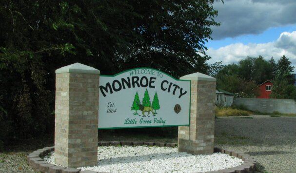 The Welcome to Monroe City sign with its pine-tree emblem.