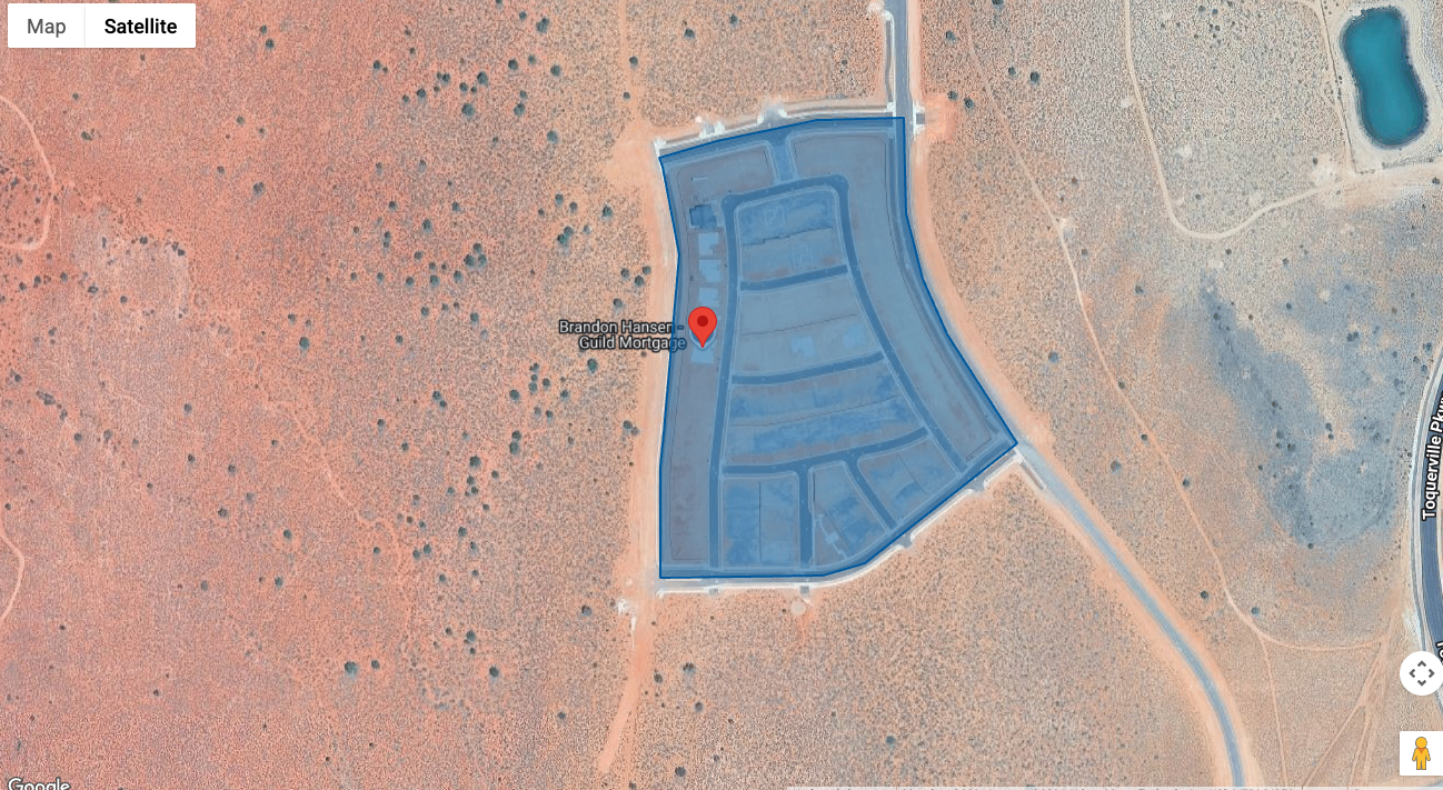 Aerial view of a fenced residential lot development outlined in blue on desert terrain